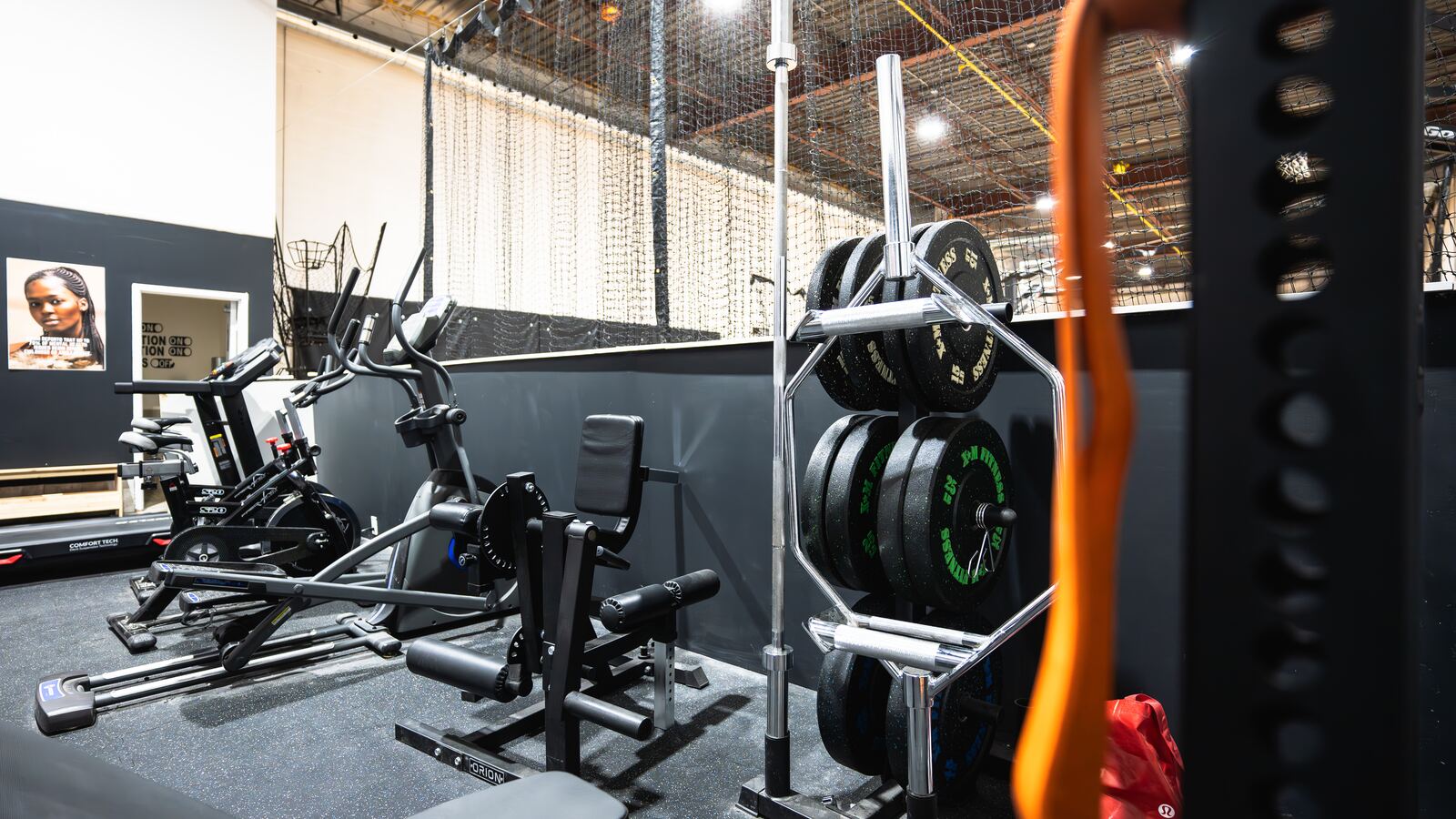 Fitness Zone with cardio machines, a leg extension station and a plate tree loaded with bumper plates